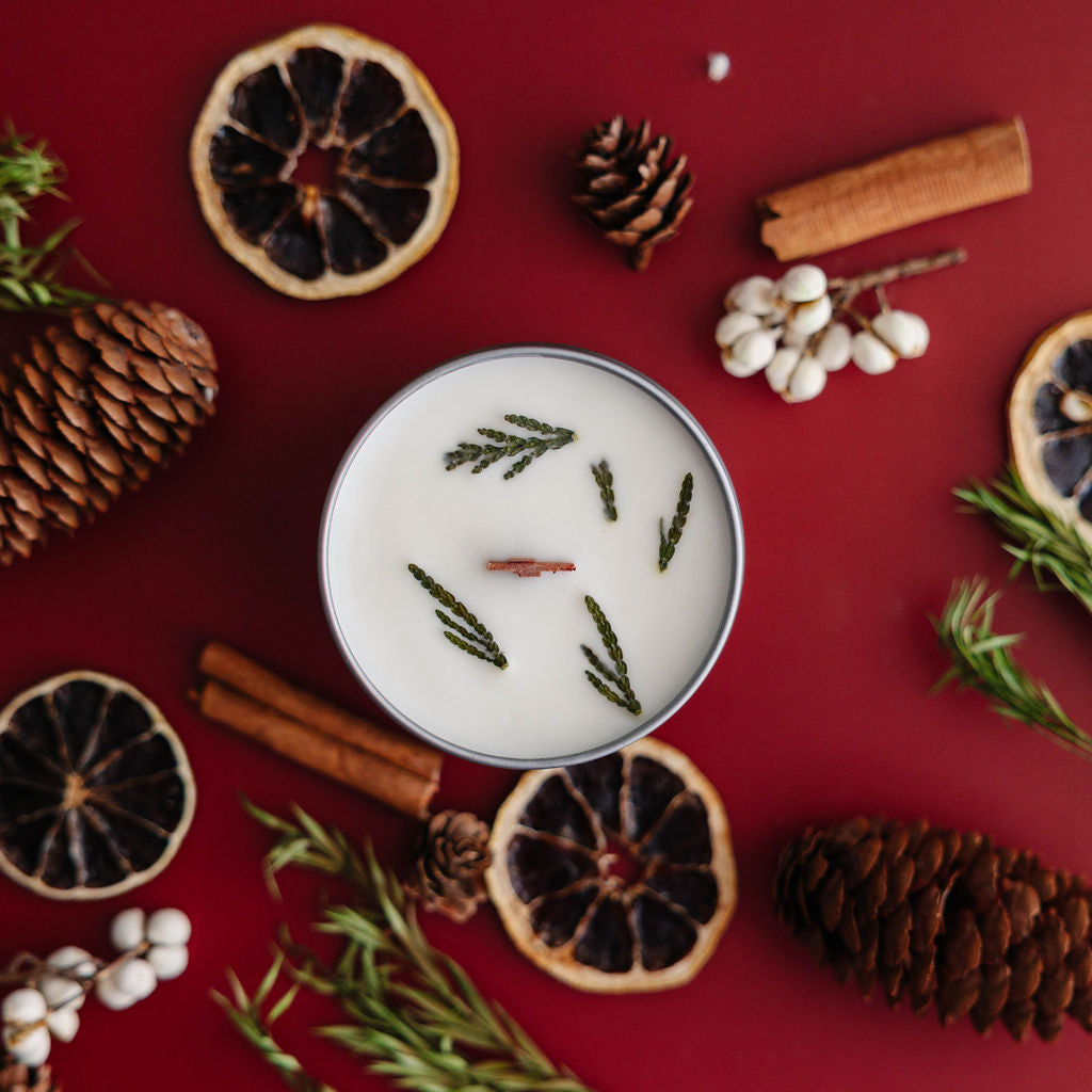 Pine candle with natural elements on a red background.